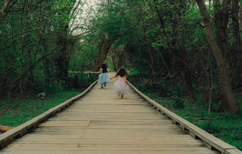 Two young girls walking together across a bridge